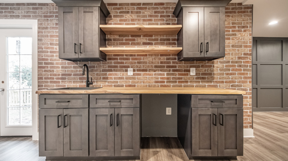 Inspiration for a mid-sized transitional single-wall wet bar in DC Metro with an undermount sink, shaker cabinets, grey cabinets, wood benchtops, red splashback, brick splashback, vinyl floors, brown floor and red benchtop.