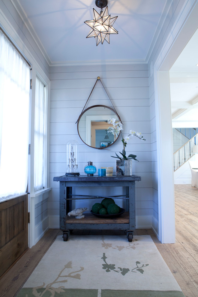 This is an example of a mid-sized beach style entry hall in New York with light hardwood floors, a single front door, grey walls, a light wood front door and beige floor.
