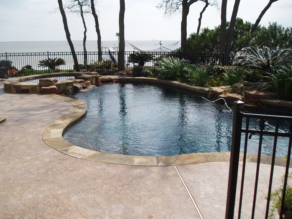 Mid-sized country backyard custom-shaped pool in Houston with stamped concrete.