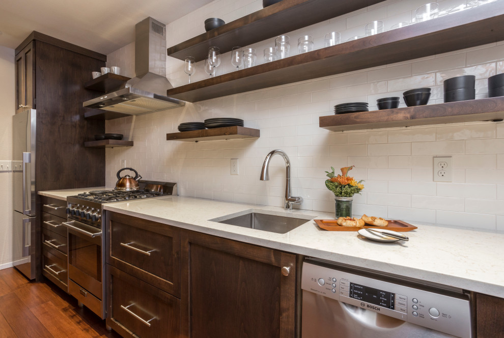 Small modern galley kitchen in Portland with shaker cabinets, brown cabinets, quartz benchtops, beige splashback, subway tile splashback, stainless steel appliances, bamboo floors, brown floor and multi-coloured benchtop.