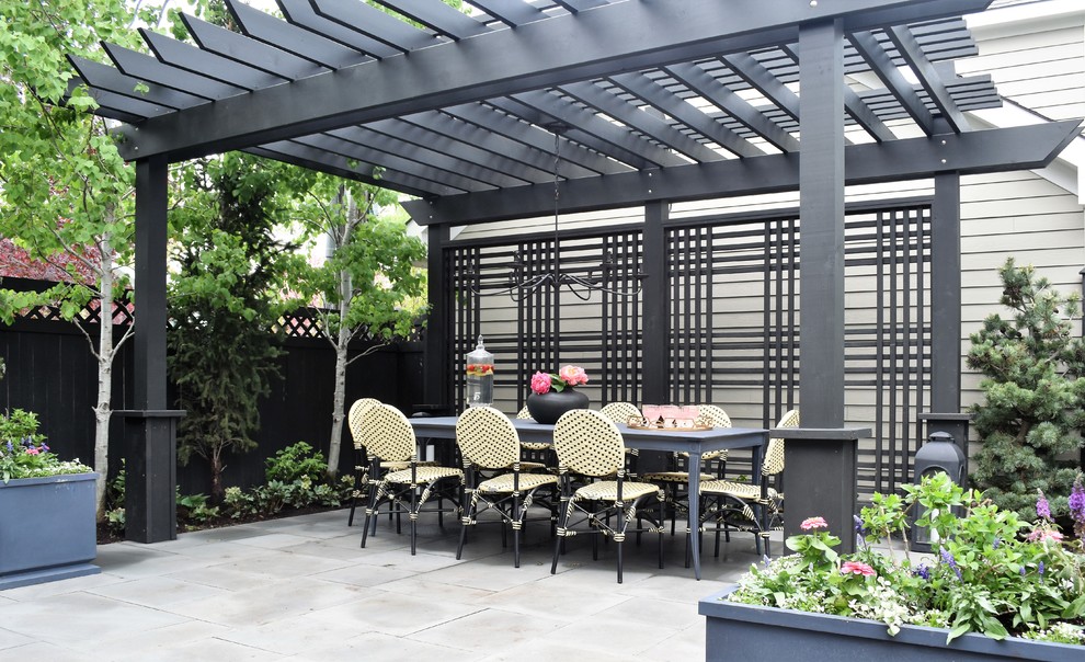 Small contemporary backyard patio in Chicago with natural stone pavers and a pergola.