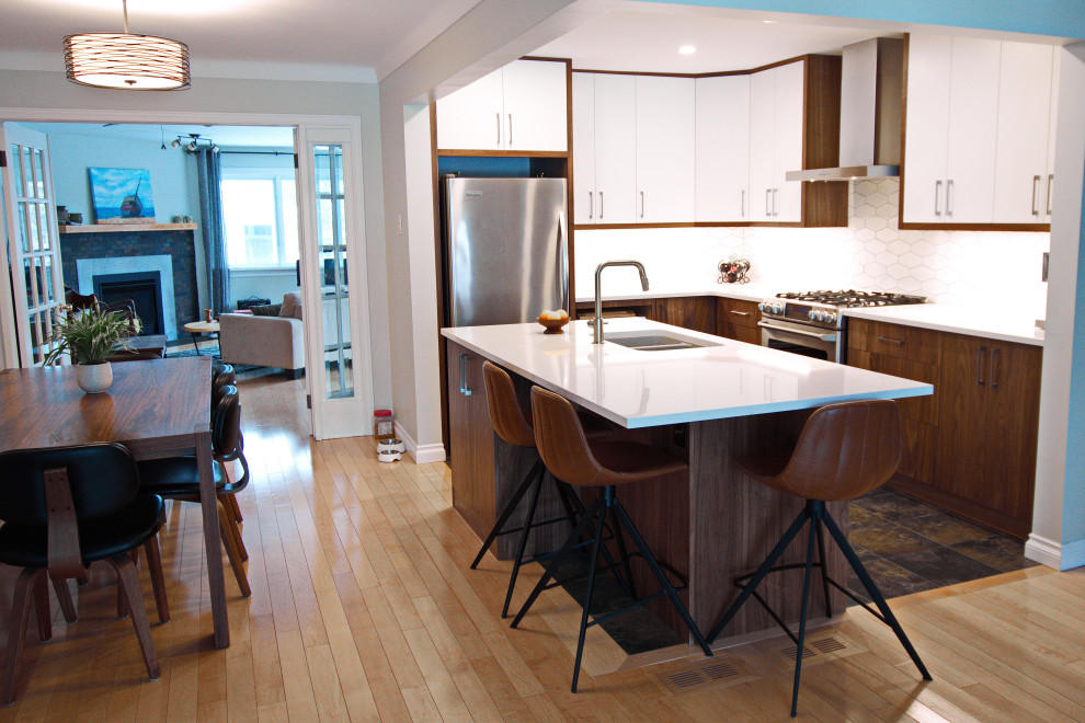This is an example of a small midcentury l-shaped eat-in kitchen in Ottawa with an undermount sink, flat-panel cabinets, white cabinets, quartz benchtops, white splashback, ceramic splashback, stainless steel appliances, slate floors, with island, multi-coloured floor and grey benchtop.