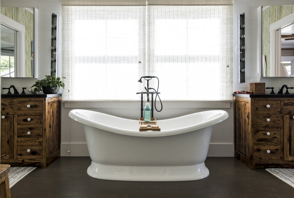 This is an example of a mid-sized country master bathroom in Louisville with distressed cabinets, a freestanding tub, white walls and cork floors.