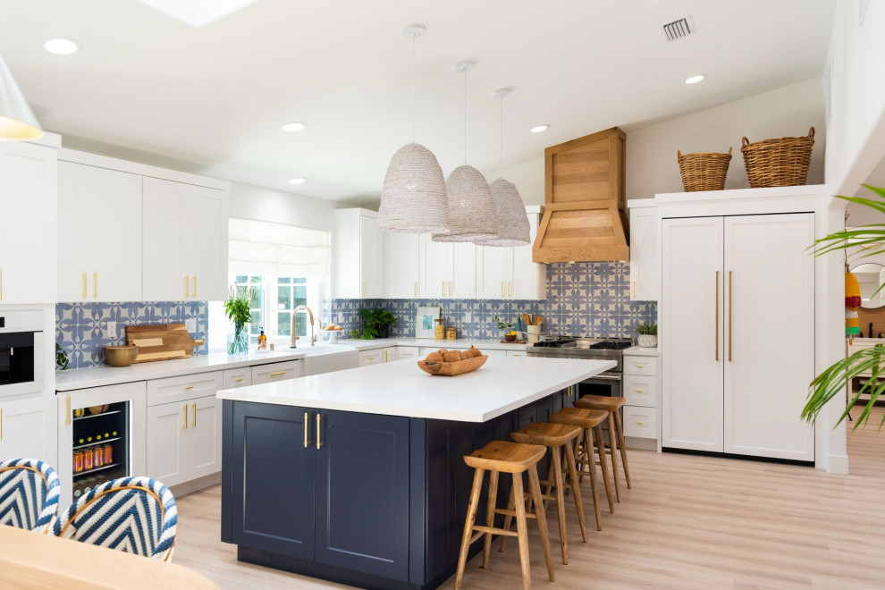 Photo of a beach style kitchen in Orange County with shaker cabinets, white cabinets, stone tile splashback and with island.
