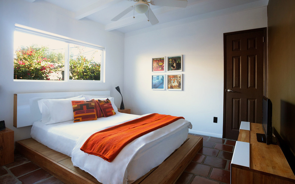 Design ideas for a mid-sized guest bedroom in Los Angeles with white walls, terra-cotta floors and no fireplace.