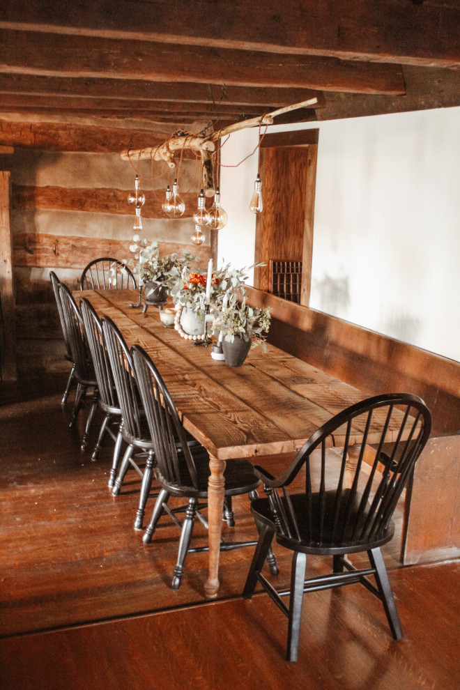 Country kitchen/dining room in Other with dark hardwood flooring, brown floors and exposed beams.