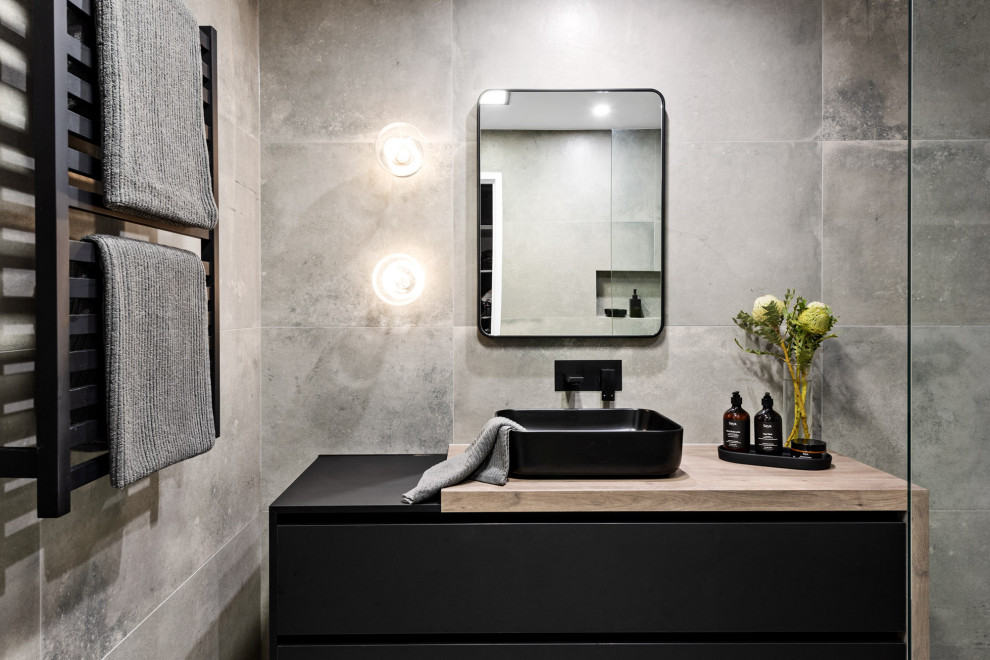 Photo of a mid-sized contemporary master bathroom in Melbourne with shaker cabinets, black cabinets, an open shower, a one-piece toilet, gray tile, cement tile, grey walls, cement tiles, a vessel sink, laminate benchtops, grey floor, an open shower, brown benchtops, a single vanity and a floating vanity.
