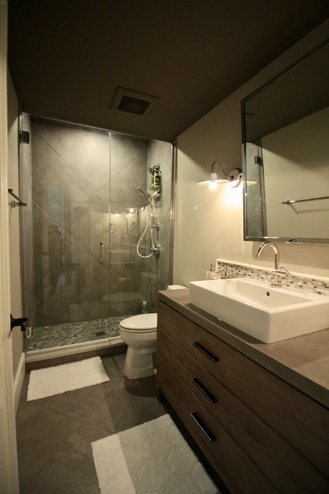 Photo of a mid-sized contemporary 3/4 bathroom in St Louis with flat-panel cabinets, distressed cabinets, a corner shower, a two-piece toilet, white tile, mosaic tile, grey walls, porcelain floors, a vessel sink and engineered quartz benchtops.