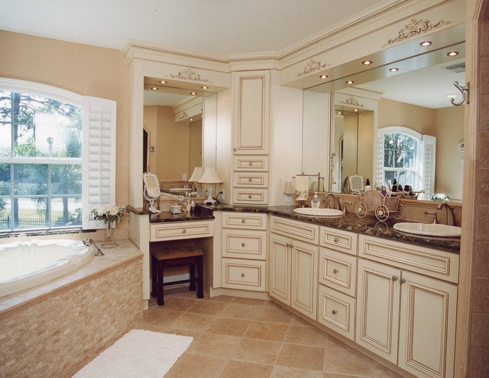 Mid-sized traditional master bathroom in Orlando with recessed-panel cabinets, distressed cabinets, a drop-in tub, beige tile, stone slab, beige walls, ceramic floors, a drop-in sink and granite benchtops.