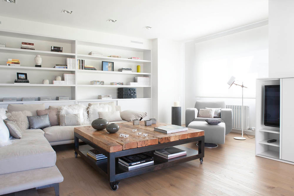 Photo of a contemporary living room in Barcelona with a library, white walls and a concealed tv.