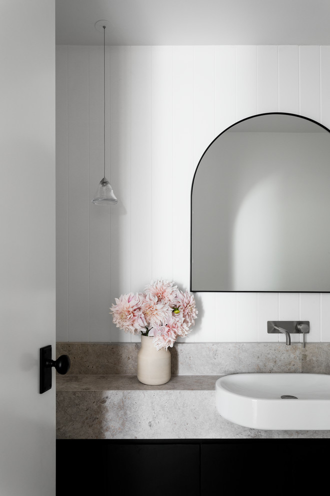 Inspiration for a contemporary powder room in Melbourne with flat-panel cabinets, black cabinets, a wall-mount toilet, white tile, mirror tile, white walls, a drop-in sink, limestone benchtops and grey benchtops.