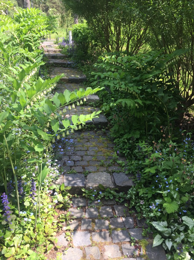 На фото: большой весенний участок и сад на внутреннем дворе в скандинавском стиле с полуденной тенью и покрытием из каменной брусчатки