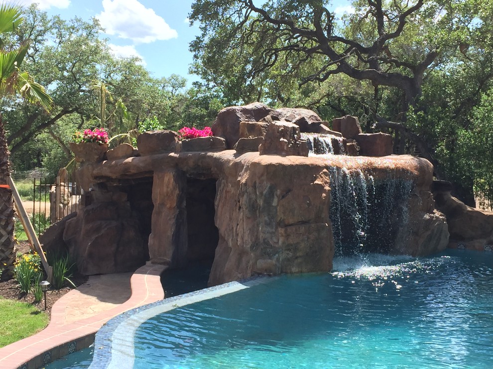 Large mediterranean courtyard custom-shaped natural pool in Austin with a water feature and stamped concrete.