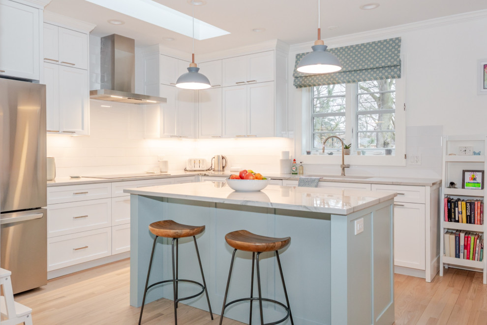 Transitional l-shaped light wood floor and beige floor kitchen photo in Chicago with an undermount sink, shaker cabinets, white cabinets, white backsplash, stainless steel appliances, an island and gray countertops