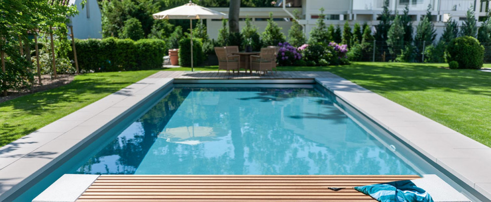 Immagine di una grande piscina minimalista con pavimentazioni in cemento