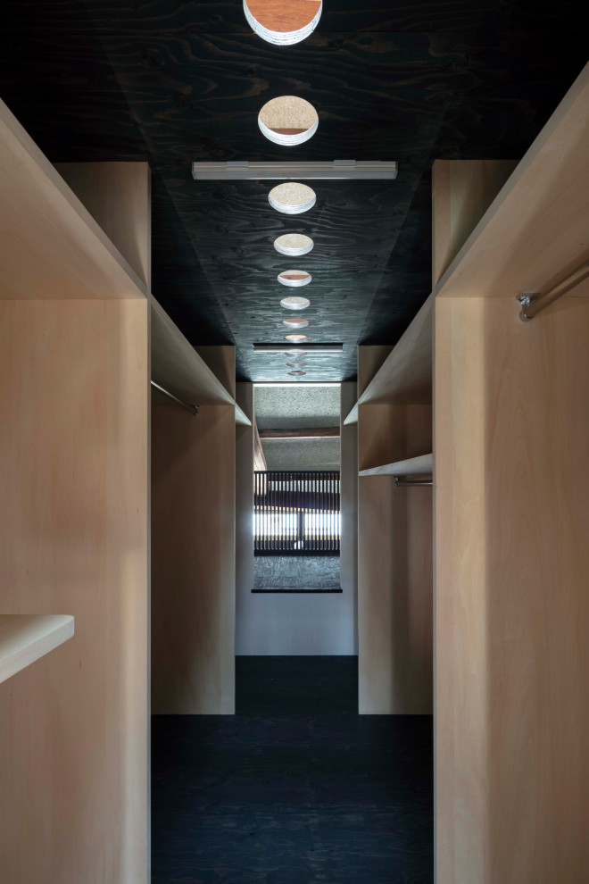 Foto di una cabina armadio unisex etnica di medie dimensioni con ante in legno chiaro, pavimento in compensato, pavimento nero e soffitto in legno