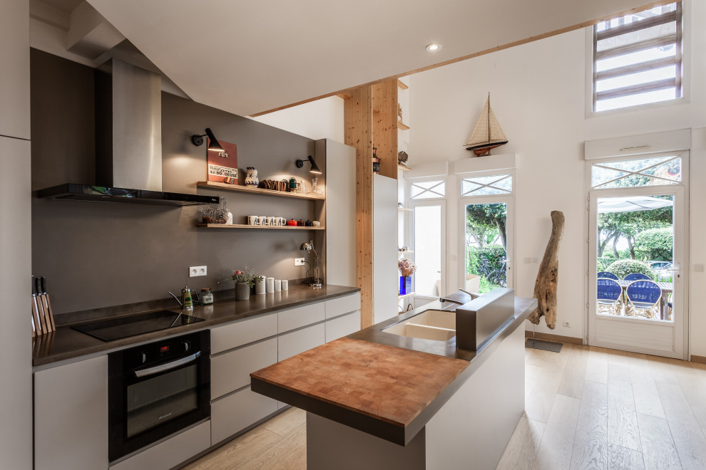 This is an example of a mid-sized contemporary galley eat-in kitchen in Bordeaux with an undermount sink, flat-panel cabinets, grey cabinets, grey splashback, panelled appliances, light hardwood floors, with island, beige floor and grey benchtop.