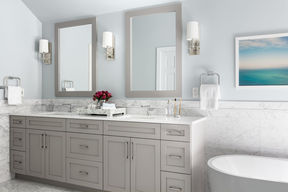 This is an example of a mid-sized transitional master bathroom in Seattle with shaker cabinets, grey cabinets, a freestanding tub, white tile, marble, grey walls, marble floors, an undermount sink, engineered quartz benchtops, white floor and white benchtops.
