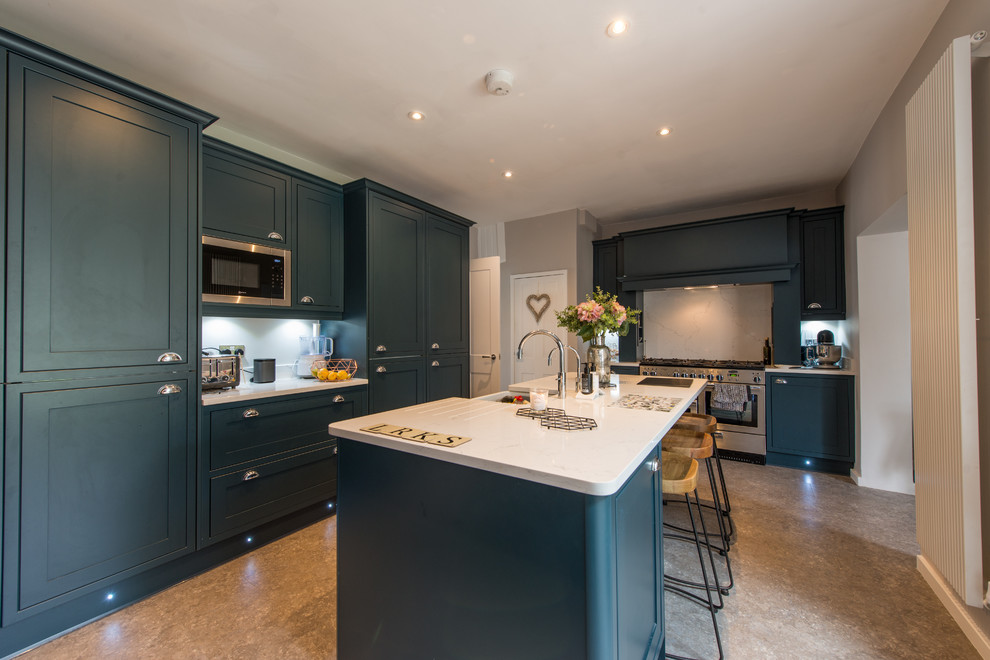 This is an example of a mid-sized transitional l-shaped open plan kitchen in London with a farmhouse sink, shaker cabinets, blue cabinets, quartzite benchtops, white splashback, stainless steel appliances, with island and white benchtop.
