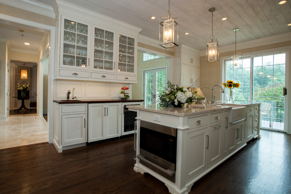 Design ideas for a large traditional galley eat-in kitchen in Philadelphia with a farmhouse sink, glass-front cabinets, white cabinets, granite benchtops, white splashback, stone tile splashback, stainless steel appliances, dark hardwood floors and with island.