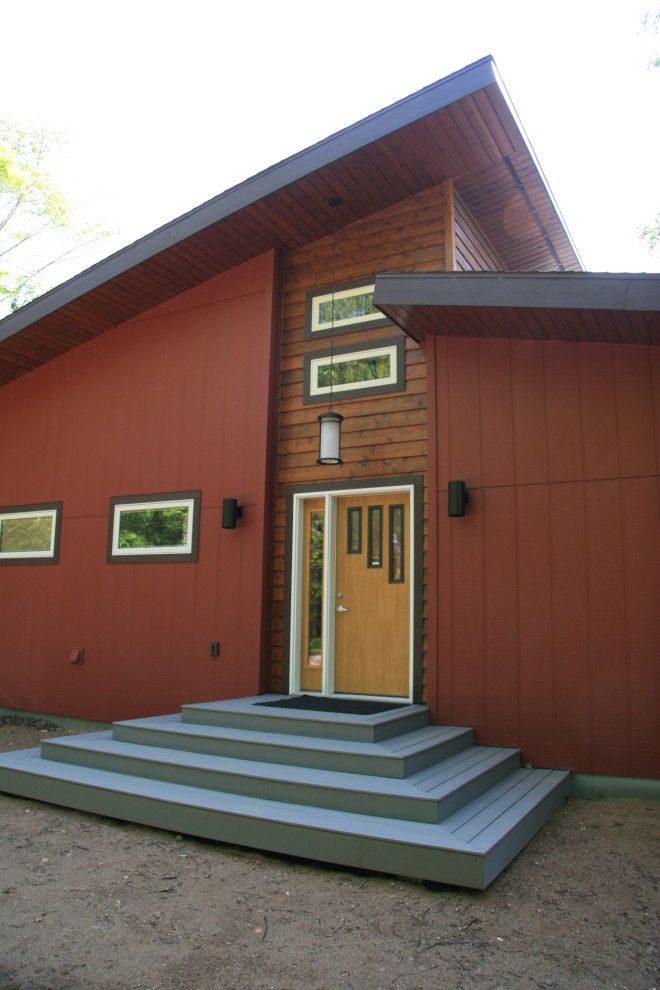 This is an example of a mid-sized arts and crafts one-storey red house exterior in Minneapolis with concrete fiberboard siding, a shed roof and a shingle roof.