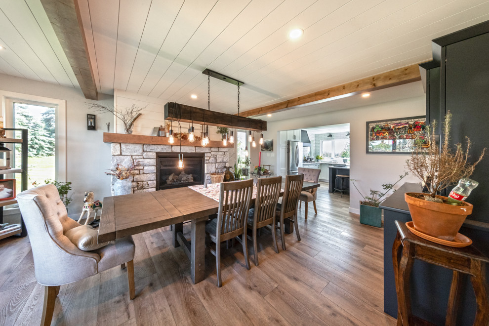 Large arts and crafts open plan dining in Edmonton with grey walls, vinyl floors, a standard fireplace, a stone fireplace surround, brown floor and timber.