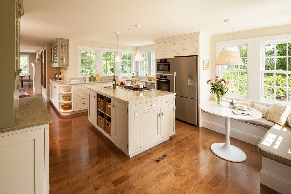 Photo of a mid-sized traditional u-shaped eat-in kitchen in Boston with an undermount sink, beaded inset cabinets, beige cabinets, quartz benchtops, beige splashback, ceramic splashback, stainless steel appliances, medium hardwood floors, with island, brown floor and beige benchtop.