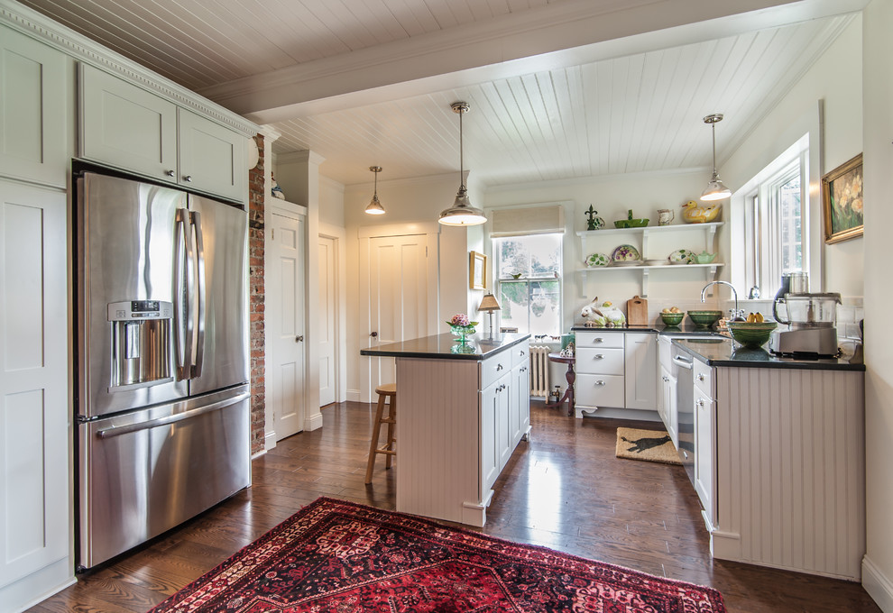 Eat-in kitchen - mid-sized country u-shaped dark wood floor eat-in kitchen idea in Providence with white cabinets, white backsplash, stainless steel appliances, an island, a farmhouse sink, flat-panel cabinets, granite countertops and subway tile backsplash