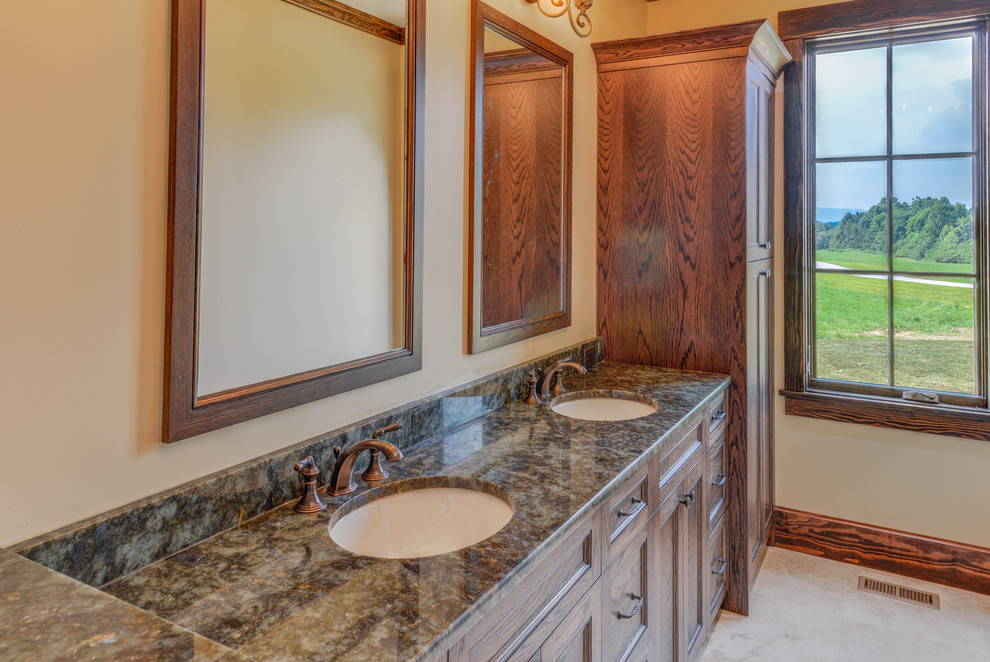 Inspiration for a mid-sized rustic master ceramic tile and beige floor bathroom remodel with recessed-panel cabinets, dark wood cabinets, beige walls, an undermount sink, granite countertops and brown countertops