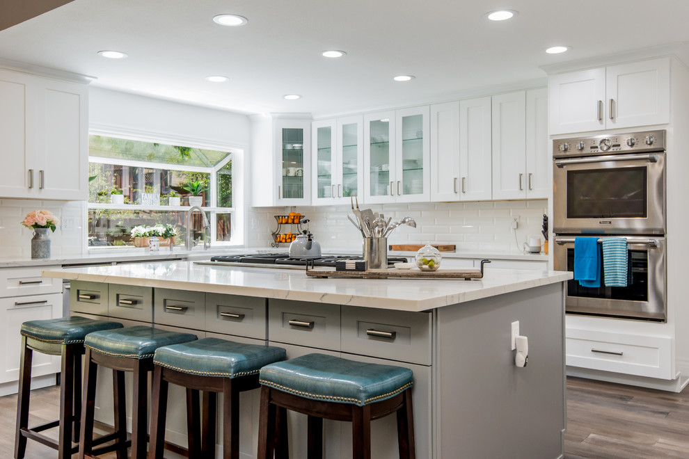 Design ideas for a large contemporary kitchen in San Francisco with an undermount sink, shaker cabinets, white cabinets, quartz benchtops, white splashback, cement tile splashback, stainless steel appliances, medium hardwood floors, brown floor and white benchtop.