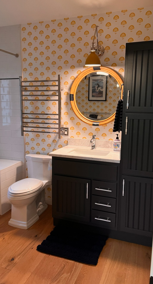 Design ideas for a beach style powder room in Los Angeles with blue cabinets, light hardwood floors, brown floor, white benchtops, a built-in vanity and wallpaper.