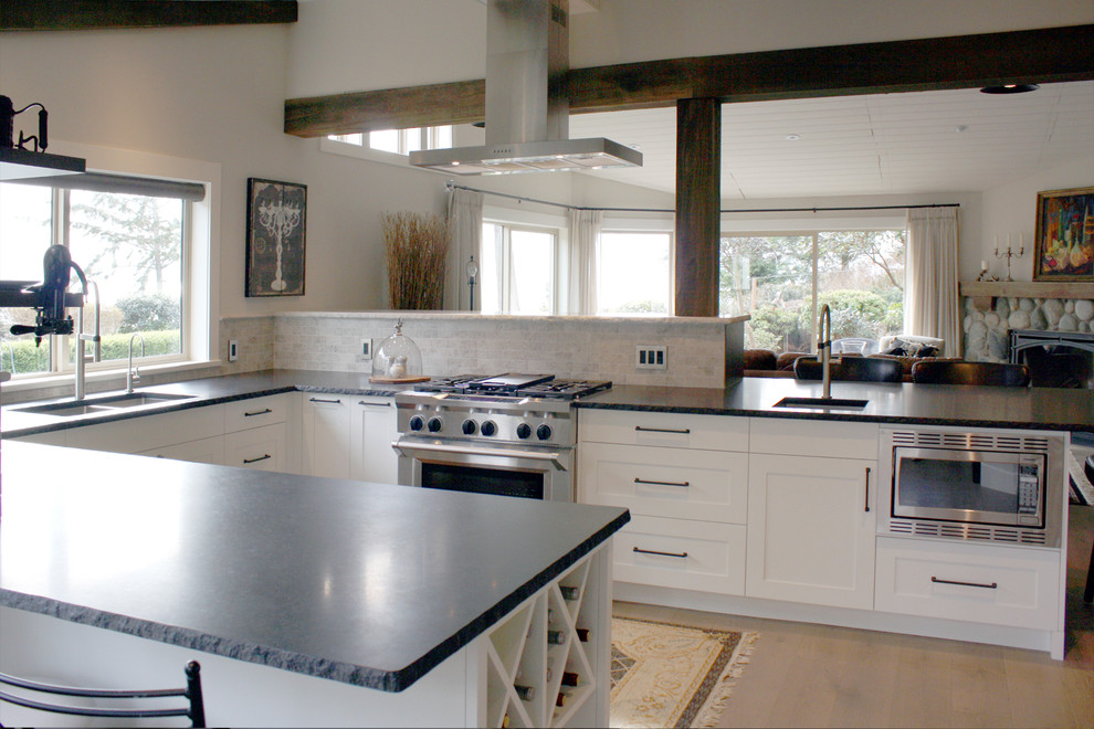 Mid-sized mountain style u-shaped medium tone wood floor open concept kitchen photo in Vancouver with an undermount sink, shaker cabinets, white cabinets, granite countertops, gray backsplash, stone tile backsplash, stainless steel appliances and a peninsula