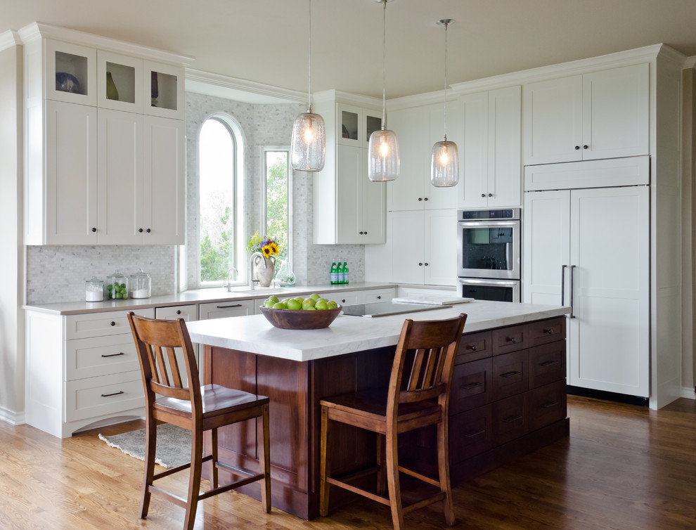 Design ideas for a traditional l-shaped open plan kitchen in Austin with an undermount sink, shaker cabinets, white cabinets, marble benchtops, white splashback, stone tile splashback, medium hardwood floors and with island.