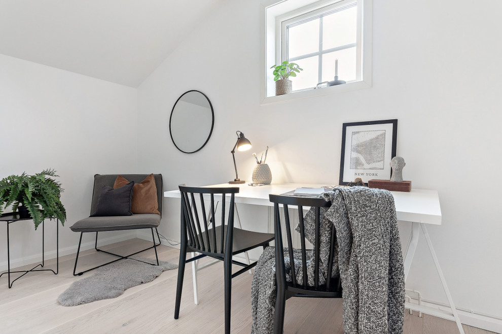 Inspiration for a mid-sized scandinavian study room in Stockholm with white walls, light hardwood floors, a freestanding desk and beige floor.