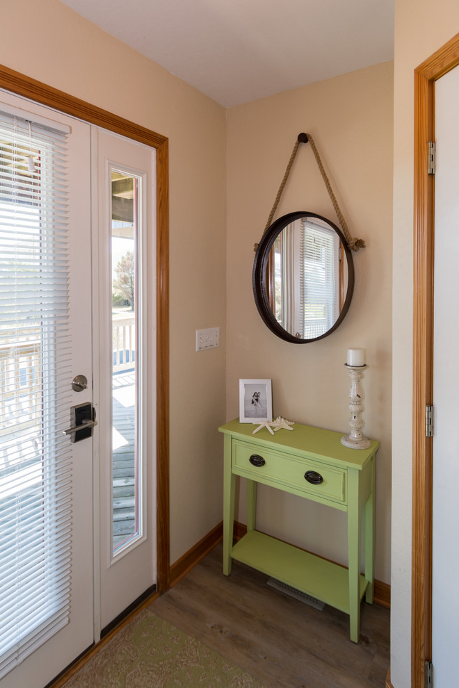 This is an example of a small beach style foyer in Other with beige walls, vinyl floors and a white front door.