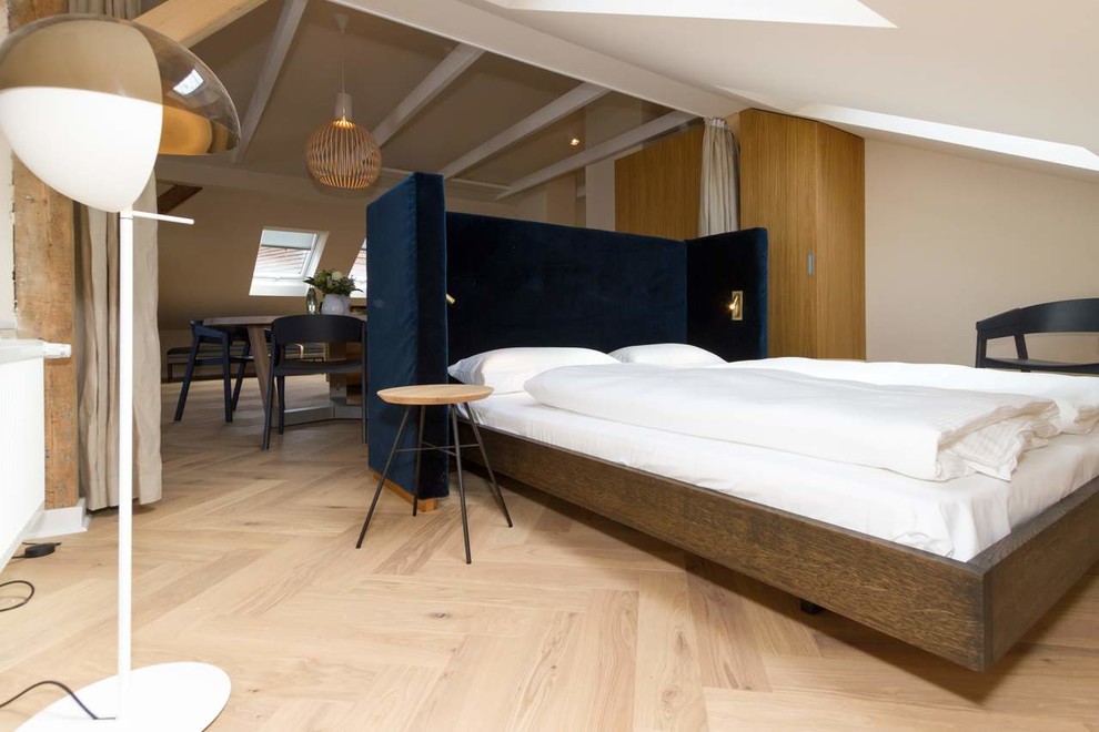 Großes Schlafzimmer im Loft-Style mit beiger Wandfarbe, braunem Holzboden und beigem Boden in Berlin