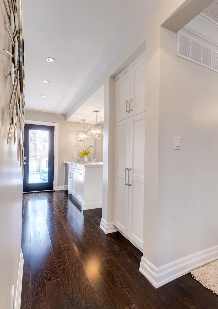 Kitchen pantry - small transitional galley dark wood floor kitchen pantry idea in Toronto with an undermount sink, shaker cabinets, white cabinets, quartz countertops, white backsplash, stone slab backsplash, stainless steel appliances and an island