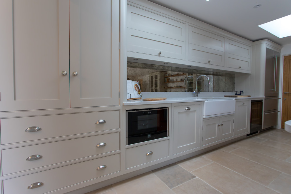 This is an example of an expansive traditional u-shaped eat-in kitchen in Hertfordshire with a farmhouse sink, shaker cabinets, grey cabinets, quartzite benchtops, metallic splashback, mirror splashback, stainless steel appliances, limestone floors, with island, beige floor and yellow benchtop.