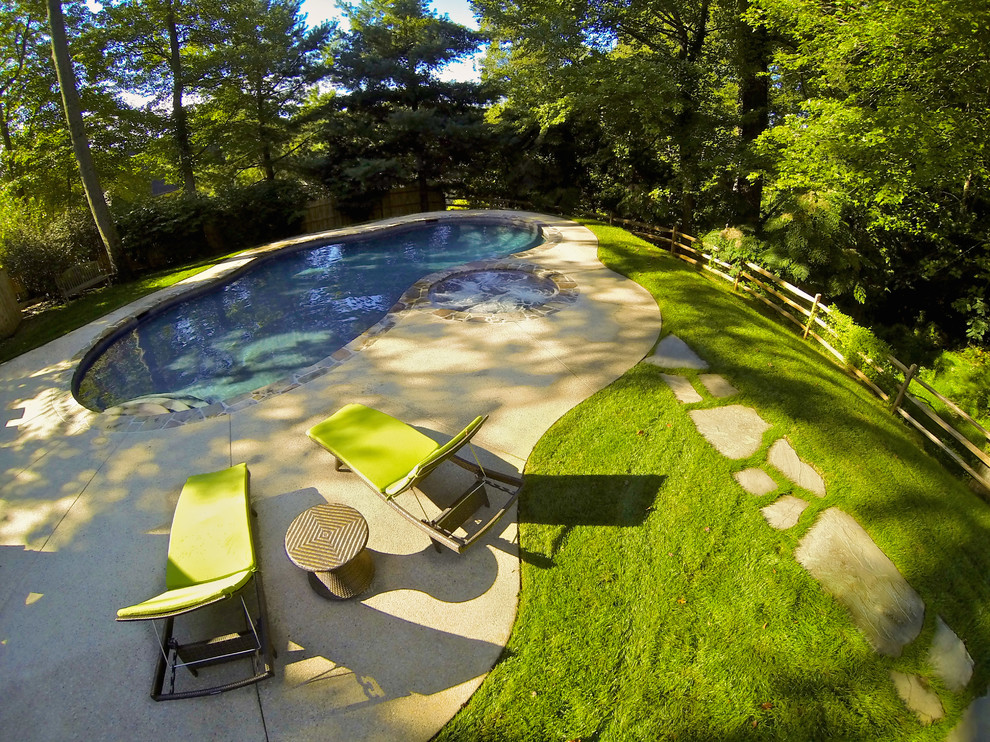 Photo of a mid-sized traditional backyard custom-shaped natural pool in Philadelphia with a hot tub and concrete slab.