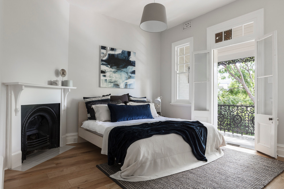 Design ideas for a large traditional master bedroom in Sydney with grey walls, medium hardwood floors, a corner fireplace and a plaster fireplace surround.