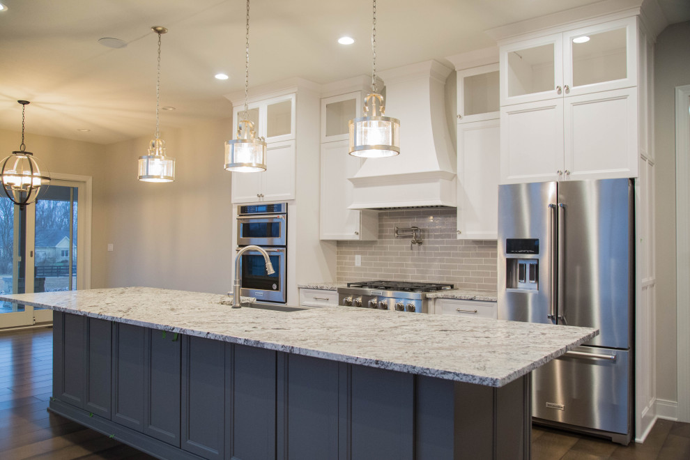 Photo of an expansive traditional single-wall kitchen in Indianapolis with a farmhouse sink, recessed-panel cabinets, blue cabinets, grey splashback, subway tile splashback, stainless steel appliances and multi-coloured benchtop.