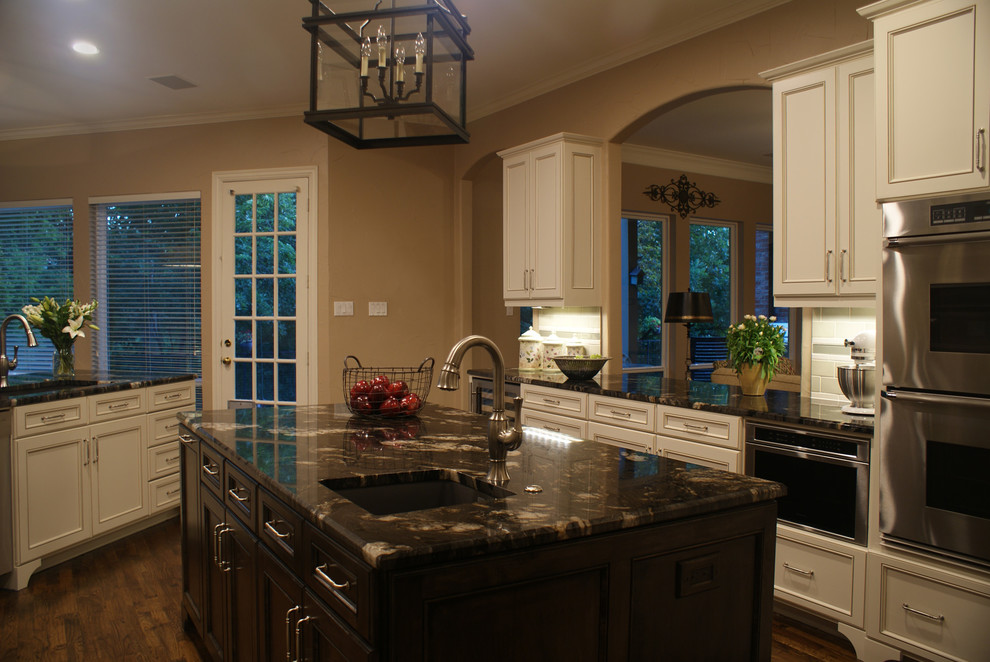 Large transitional u-shaped medium tone wood floor kitchen photo in Dallas with an undermount sink, flat-panel cabinets, white cabinets, granite countertops, green backsplash, ceramic backsplash, stainless steel appliances, beige walls and an island