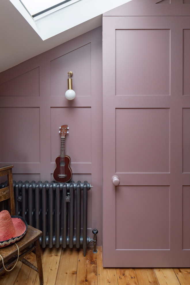 Immagine di un soggiorno bohémian di medie dimensioni e aperto con libreria, pareti rosa, pavimento in legno massello medio, TV nascosta e pannellatura
