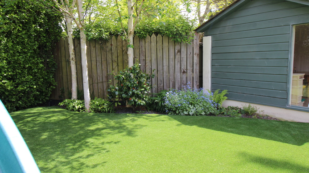 Inspiration for a small contemporary backyard full sun formal garden for summer in Dublin with with lawn edging, mulch and a wood fence.