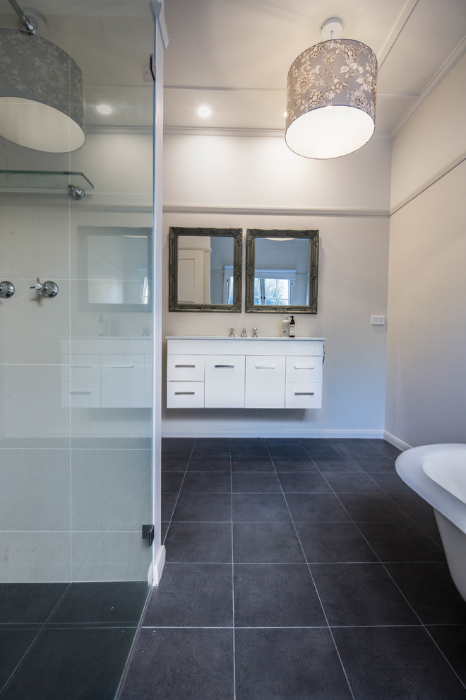 Inspiration for a mid-sized traditional kids bathroom in Canberra - Queanbeyan with furniture-like cabinets, white cabinets, a claw-foot tub, an alcove shower, cement tile, beige walls, porcelain floors, an integrated sink, engineered quartz benchtops, grey floor, a hinged shower door and white benchtops.