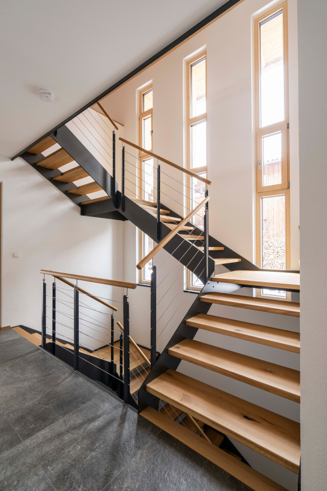 Cette photo montre un escalier tendance avec des marches en bois et un garde-corps en métal.