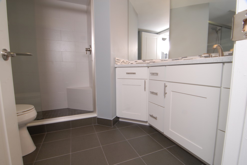 This is an example of a beach style bathroom in Miami with glass tile, shaker cabinets, white cabinets, white tile, ceramic floors, an integrated sink, solid surface benchtops, grey floor and a sliding shower screen.