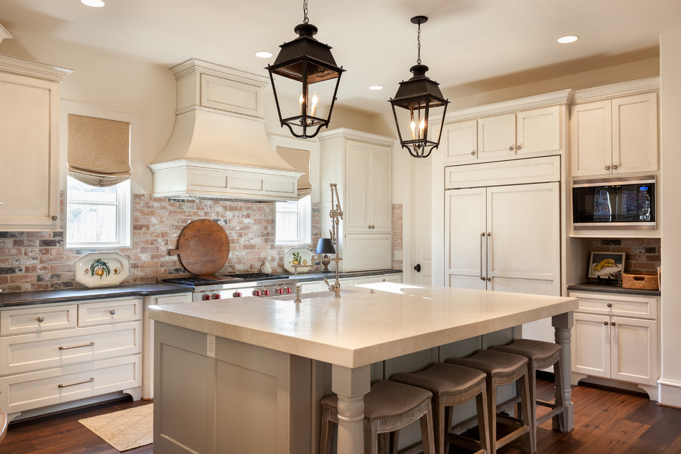 Photo of a large traditional u-shaped eat-in kitchen in Houston with a farmhouse sink, shaker cabinets, white cabinets, panelled appliances, dark hardwood floors, with island, soapstone benchtops and brick splashback.