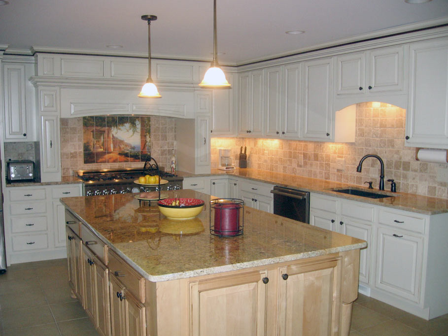 Photo of an eat-in kitchen in Cleveland with a drop-in sink, louvered cabinets, white cabinets, beige splashback, ceramic splashback, stainless steel appliances, ceramic floors and with island.