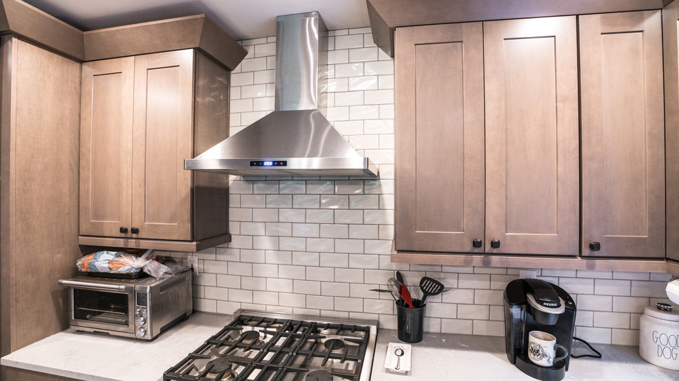 Inspiration for a large transitional l-shaped vinyl floor and brown floor open concept kitchen remodel in Seattle with an undermount sink, recessed-panel cabinets, medium tone wood cabinets, quartz countertops, white backsplash, subway tile backsplash, stainless steel appliances, an island and white countertops